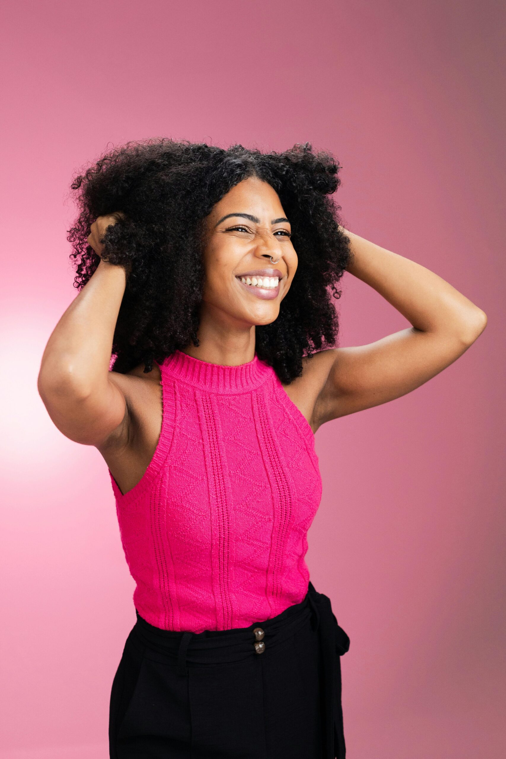 black woman smiling confidently. wearing pink top and natural hair